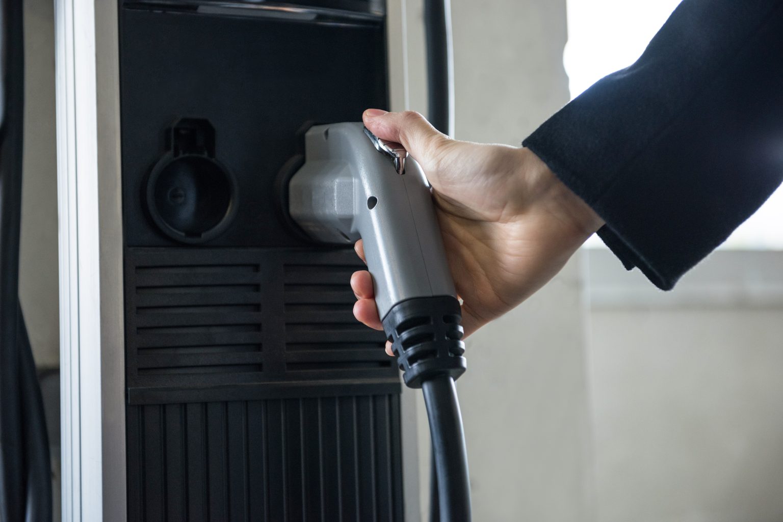 Close-up of man charging car at electric vehicle charging station